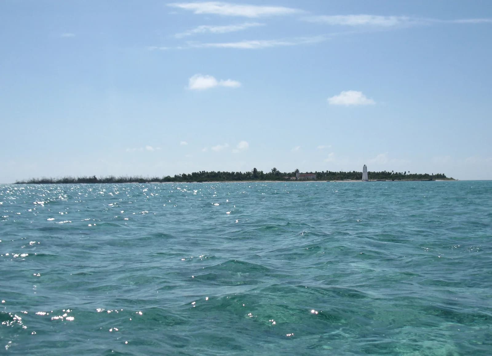 Low sandy cay with scrub vegetation and shallow turquoise reef flats at Cayo Norte, Banco Chinchorro, Mexico
