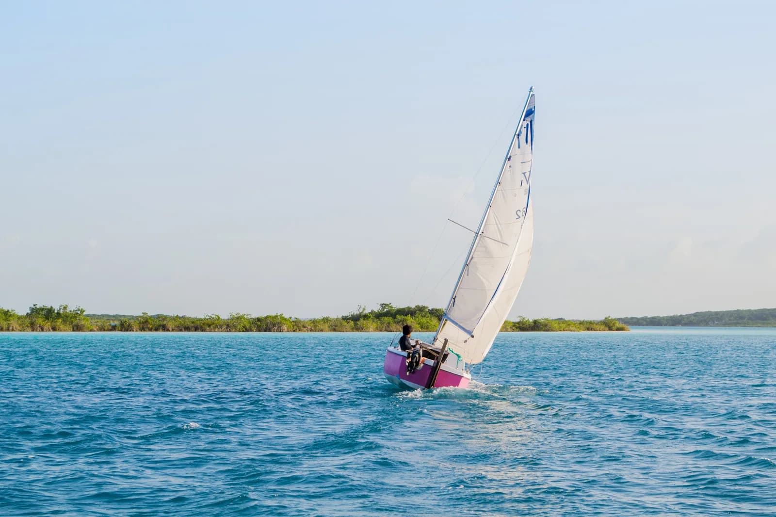 A sailboat on the turquoise water of Bacalar lagoon, the Lake of Seven Colours, near Costa Maya