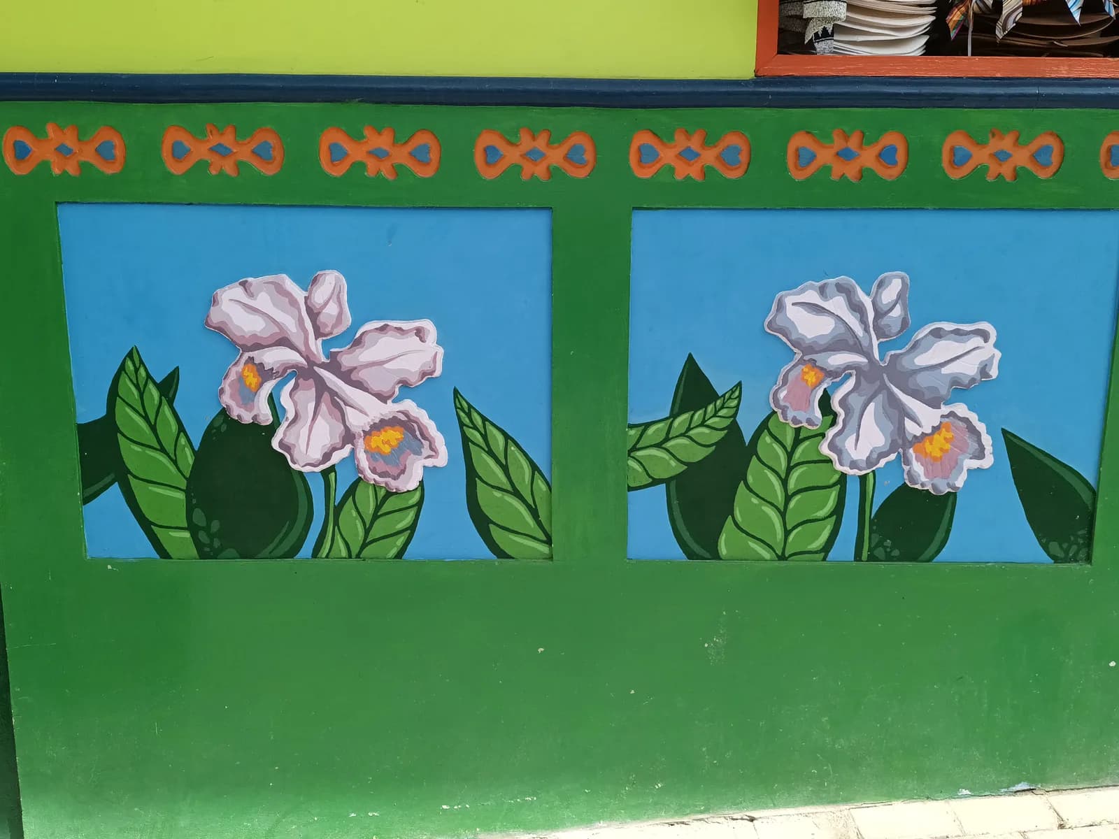 A street in Guatapé lined with brightly painted houses, each with decorative zócalo panels along the lower walls