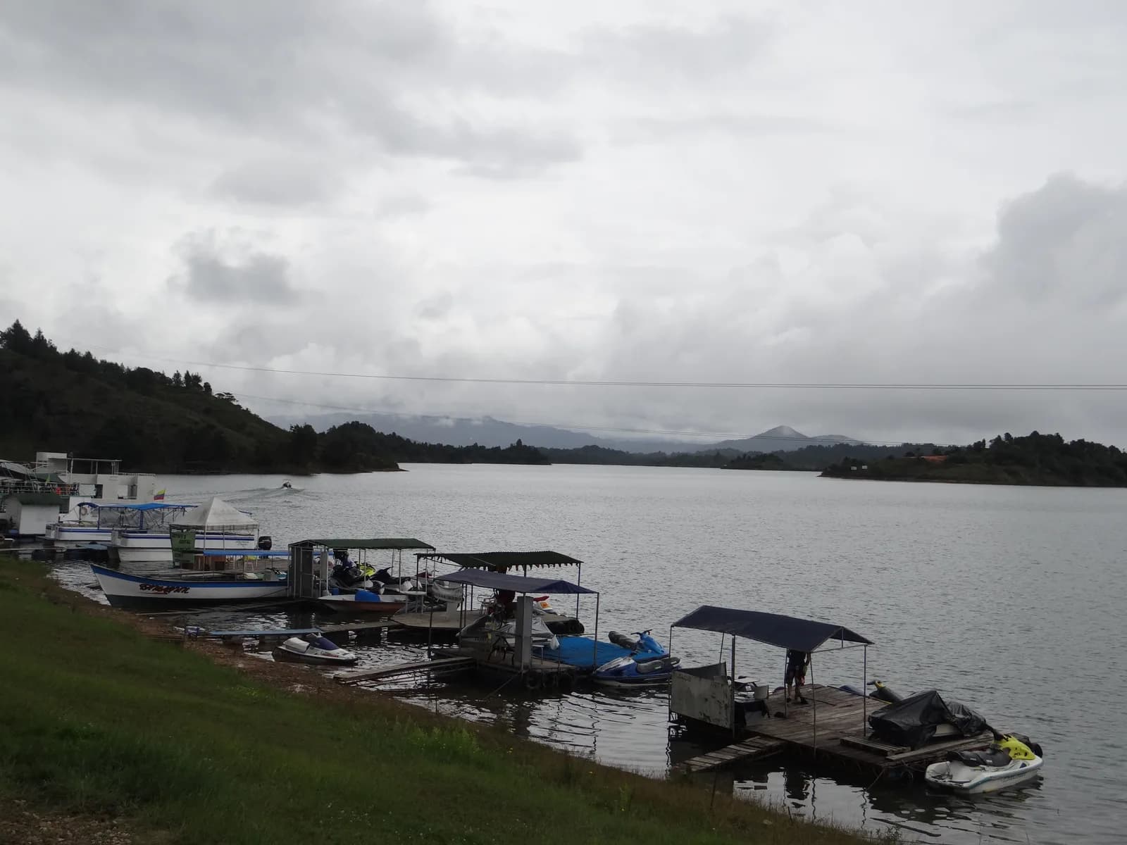 The malecón waterfront promenade in Guatapé with boats moored on the reservoir and hills behind
