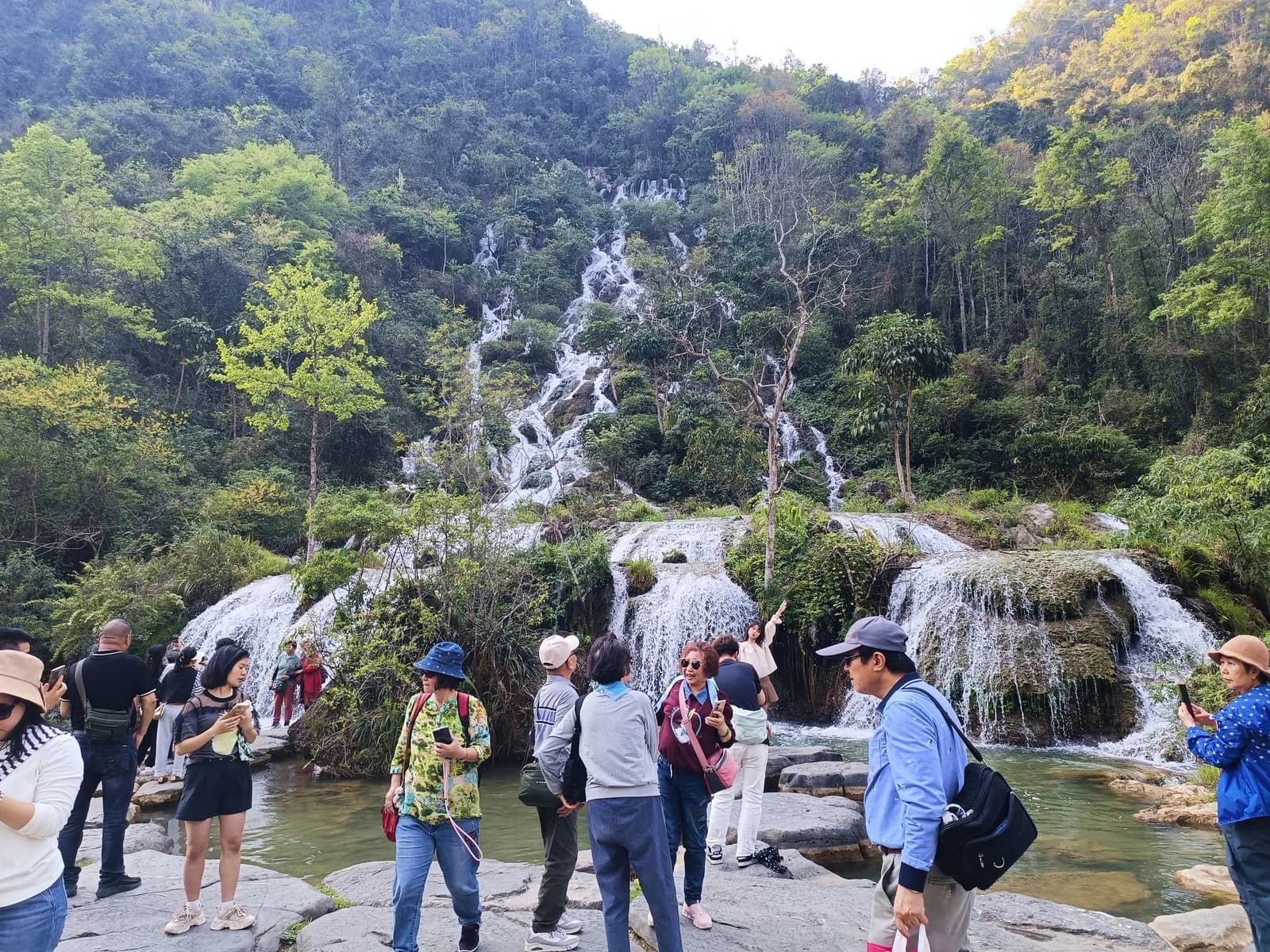 Tour groups gathered on the rocks below the wide Cuigu Waterfall at Xiaoqikong in March
