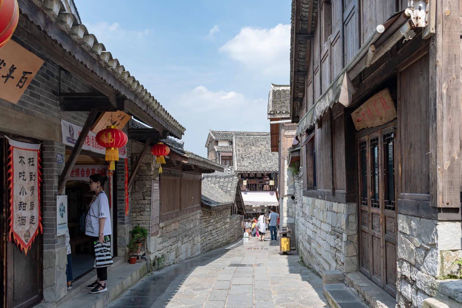 Narrow stone-paved lane between old timber and stone buildings in Qingyan Ancient Town with red lanterns