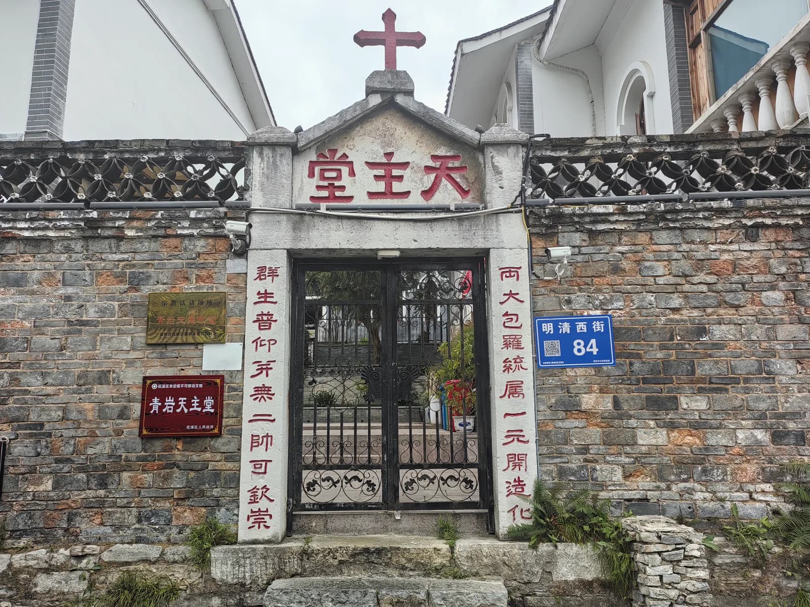 Stone gateway of the Qingyan Catholic Church with Chinese characters above an iron gate and a cross on top