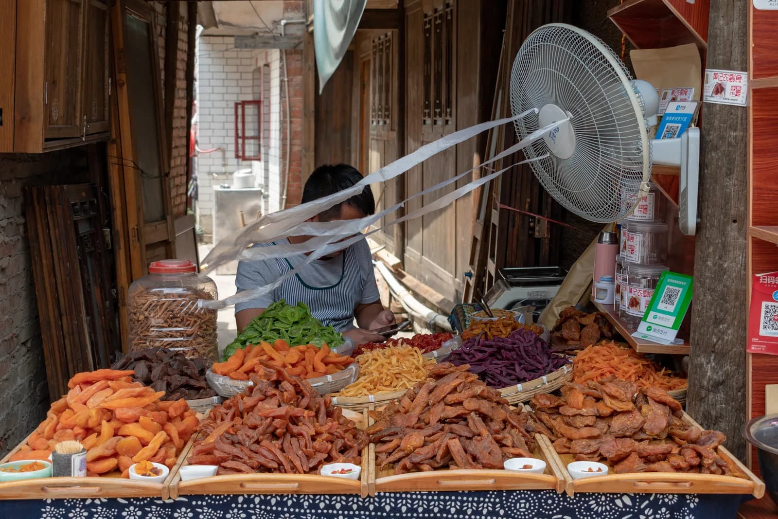 Snack stall in Qingyan Ancient Town with trays of braised and dried foods under a timber shopfront