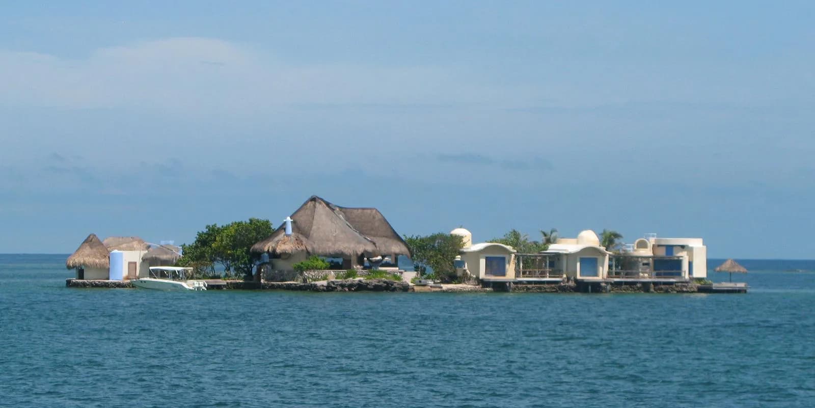 A tiny islet in the Rosario archipelago with thatched-roof huts and white buildings on the water near Cartagena