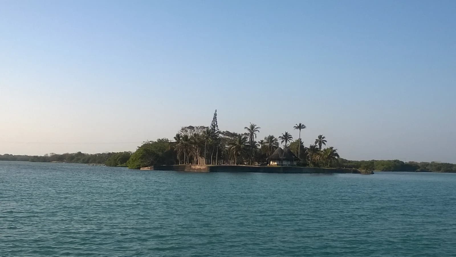 A palm-covered island with a thatched hut seen from the water in the Rosario Islands off Cartagena