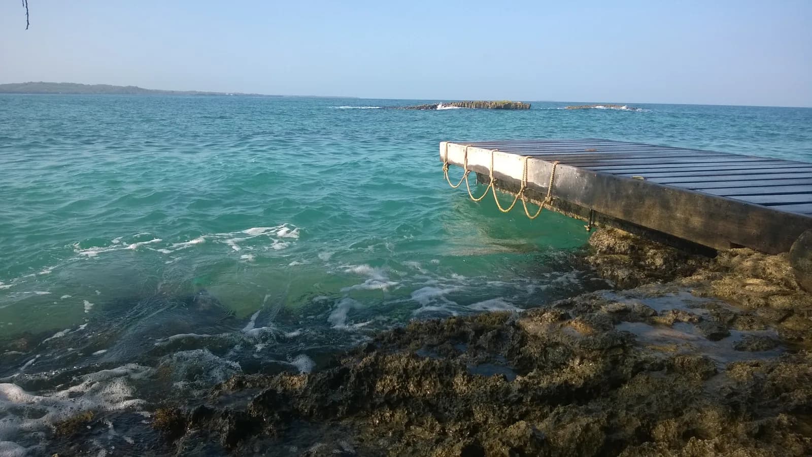 Wooden jetty over clear turquoise water on the coral shoreline of the Islas del Rosario near Cartagena
