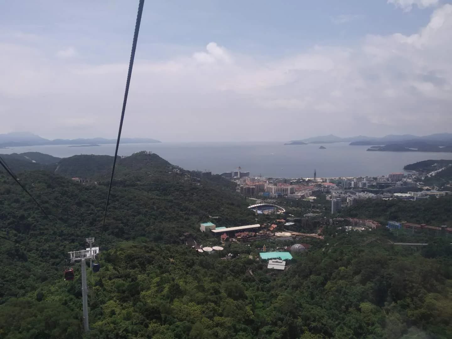 View from the OCT East cable car over forested hills down to the theme park and Dameisha bay in Shenzhen