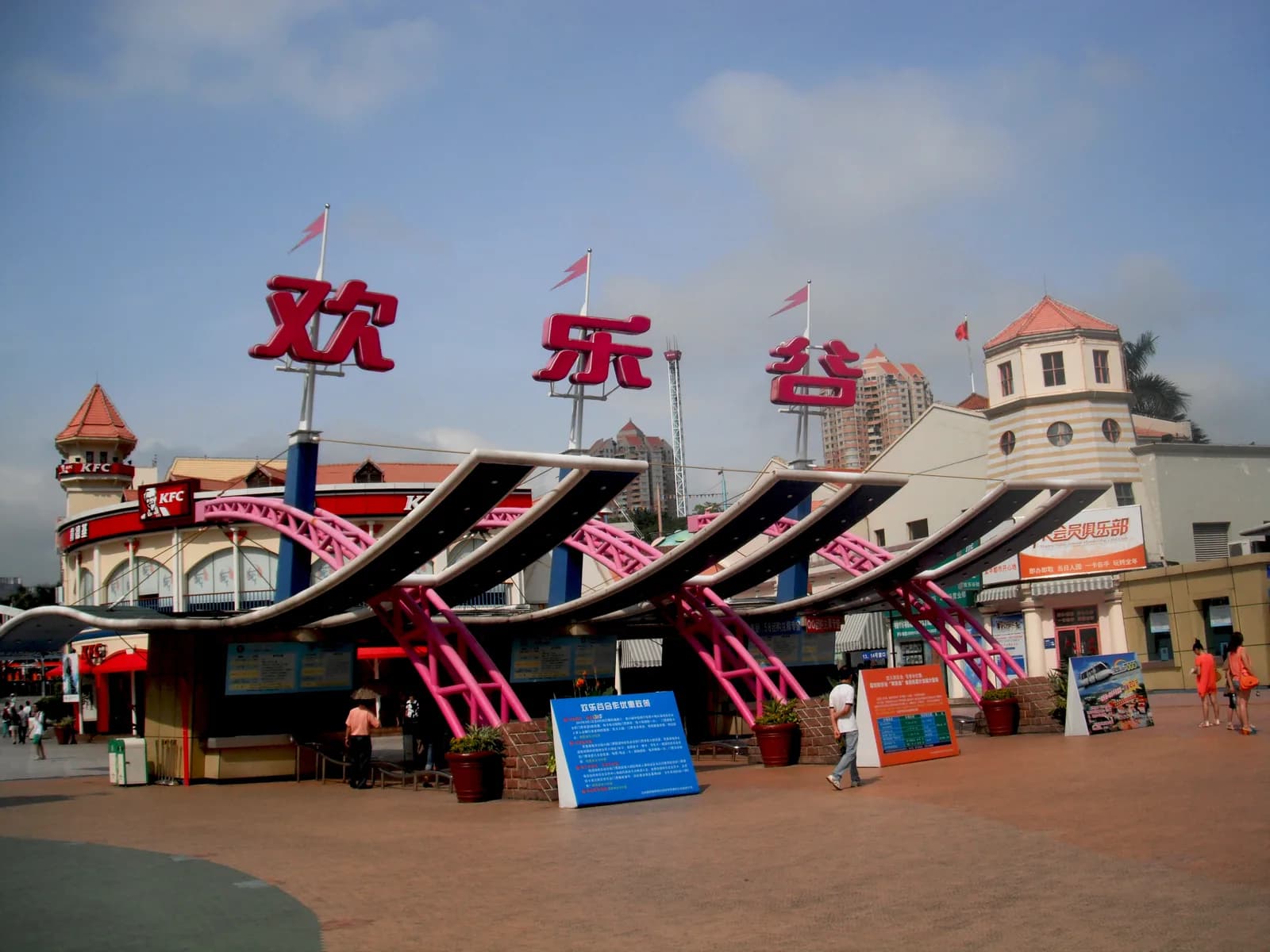 The main gate of Happy Valley Shenzhen with the large red Chinese characters and pink roller coaster track sculptures