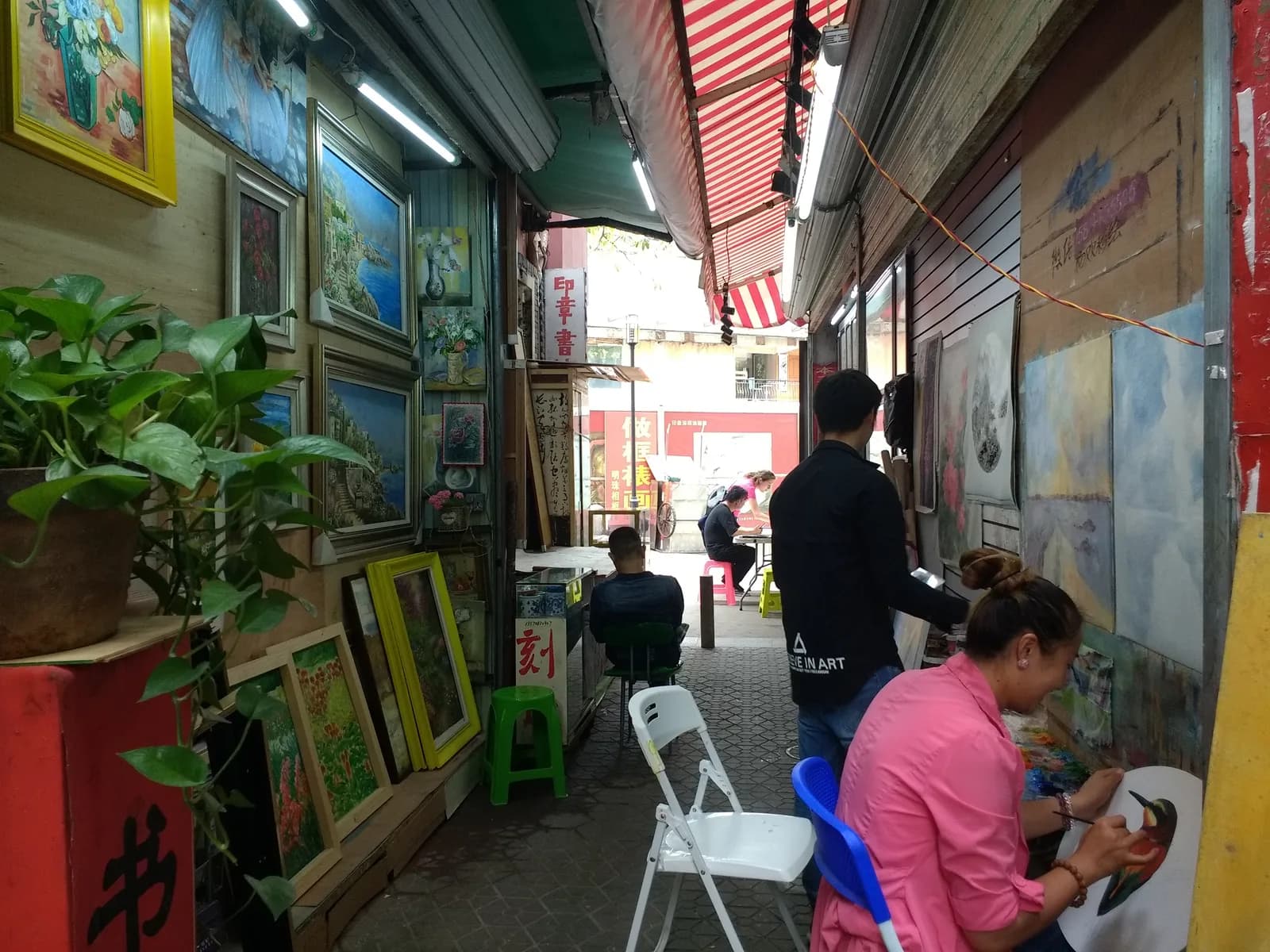 Artists painting canvases in an open studio at Dafen Oil Painting Village in Shenzhen
