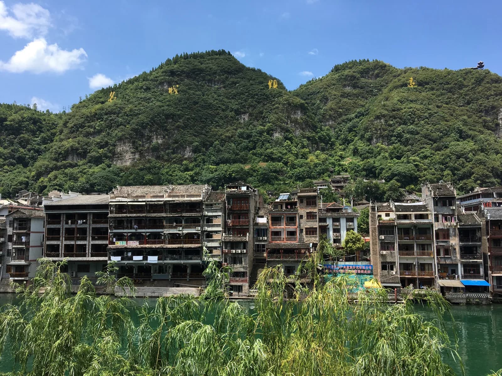 Traditional tiled houses of Zhenyuan ancient town stacked along the green Wuyang River in Guizhou, China