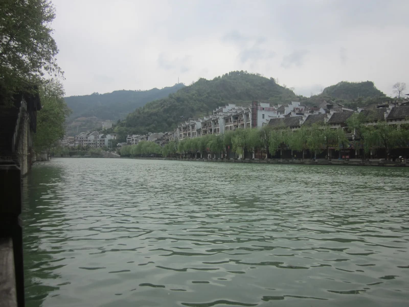 Boats moored on the calm green Wuyang River between the old town banks of Zhenyuan County